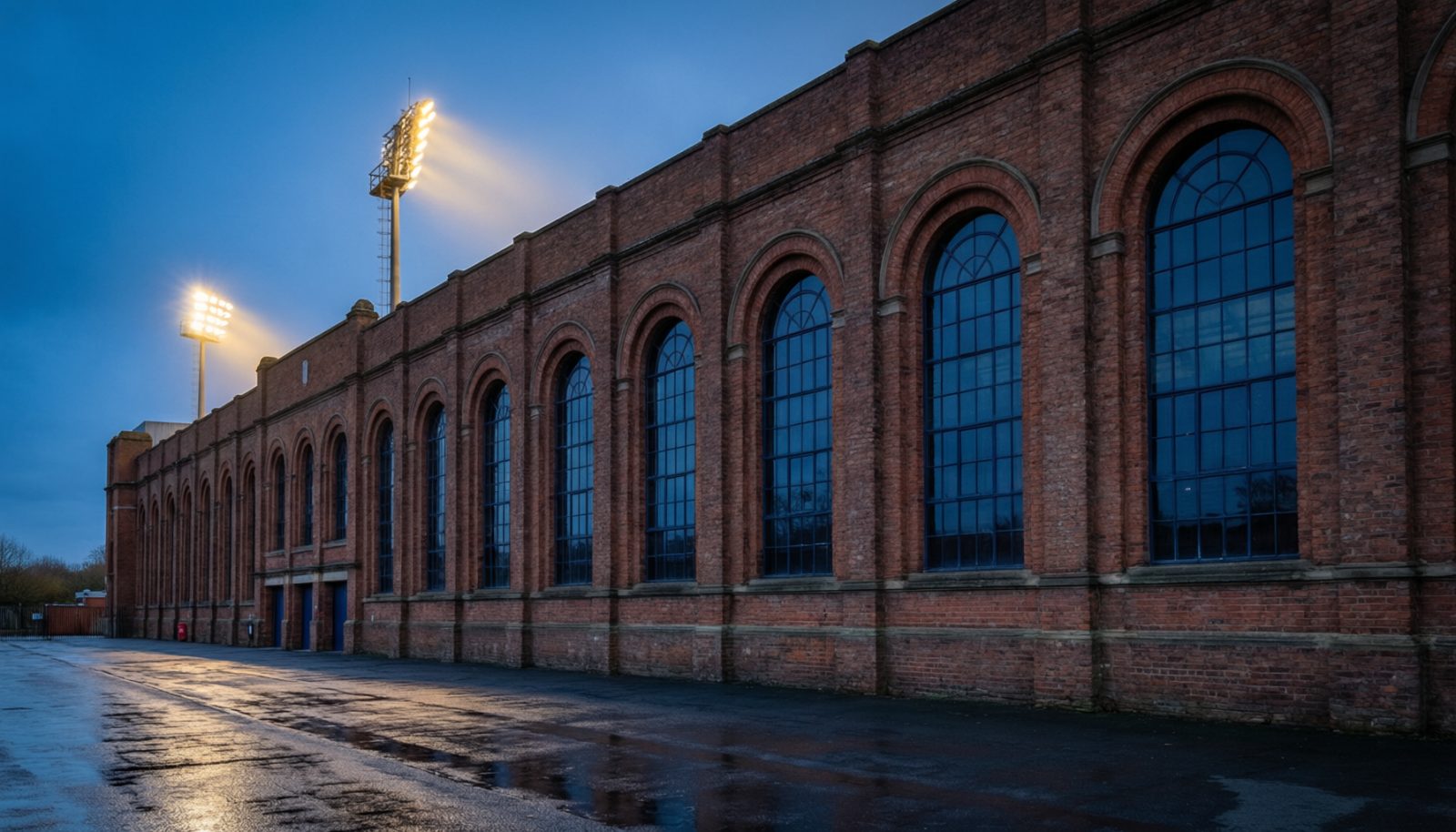 云开全站app官方网站 - AI生成示意图:黄昏时分的英格兰球场砖砌外立面与泛光灯
